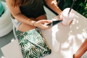 woman looking at her phone while drinking a milkshake
