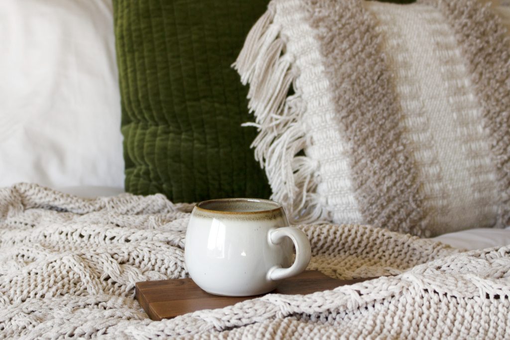 coffee mug on a coaster on a bed