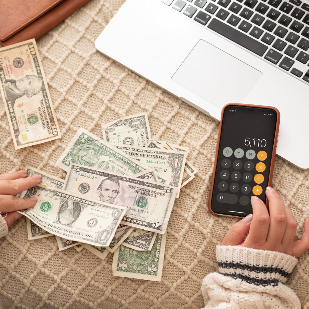 woman using a calculator while counting money